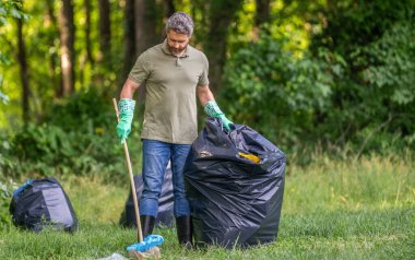 Çevre eylemcisi. Çevre koruma ve atık kirliliği. Çevre plastik kirliliği. Ormandaki çöpleri poşete doldurmaya gönüllü. Çevresel koruma. Orman gönüllüsü.