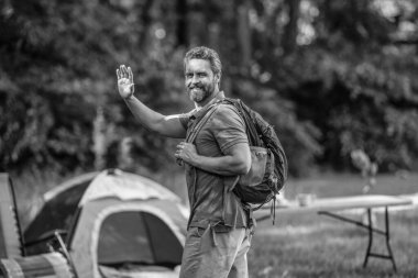 Ormanda çadırlı sırt çantalı bir adam. Yaz günü doğa yürüyüşçüsü. Yaz kampı ve doğa tatili. Yaz kampındaki adam. Kamp macerası. Yürüyüş konsepti. Kamp çadırı. Merhaba..