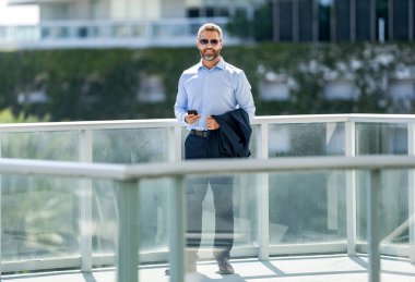 İş adamı telefonda sohbet ediyor. Akıllı telefon kullanan bir iş adamı. Başarılı bir iş adamı internette sohbet ediyor. Dışarıdaki iş adamı. İş adamı cep telefonuyla konuşuyor. İş sohbeti.