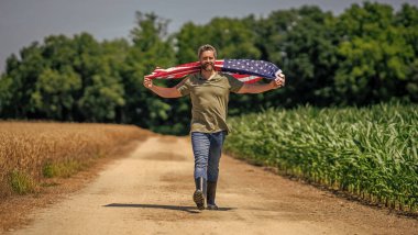 Amerikan bayrağı ve çiftçi adam. ABD bayrağı. Bağımsızlık Günü. Sahadaki adam. Ekin tarlasında Amerikan bayrağı taşıyan adam. Amerika 'nın Bağımsızlık Günü. 4 Temmuz. Amerikan İşçi Bayramı. Ulusal vatanseverlik.