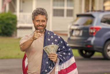 Amerikan vergi politikası. İspanyol adam ve Amerikan bayrağı. Amerika 'da vergi ödemek. Katma değer vergisi. Vergi sistemi. Vatansever adam. Amerikan bayrağı ve dolar parası olan adam. Enflasyon konsepti. İşaret parmağı.