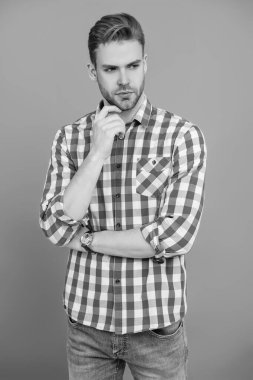 Kareli gömlek giyen milenyum adamı. Milenyum erkeğinin gündelik tarzı. Sıradan tişörtlü bir adamın portresi. Tıraşsız adamın zarif portresi. Gri yolda izole edilmiş bir adam. Günlük kıyafet..