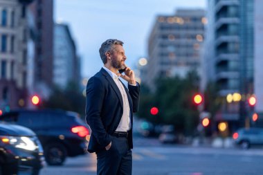 Takım elbiseli bir adam telefonda konuşuyor. Telefonu olan olgun bir İspanyol iş adamı. İş adamlarının iş iletişimi. İş adamı dışarıda telefonla konuşuyor. İş adamı afişi.