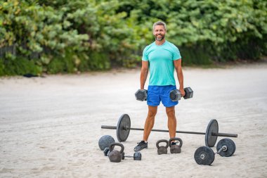 Jimnastik. Dambılı bir sporcu. Sağlıklı bir yaşam tarzı. Kas gücü. Güçlü trisepsler. Dambılla egzersiz yapan bir adam. Erkek atlet dambılı kaldırıyor. Güçlü adam spor yapar, afiş.