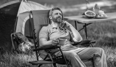 İlham konsepti. Kamp çadırı. Kahve fincanı. Adam ormanda sabah kampı kahvesi içiyor. Yaz günü doğa yürüyüşçüsü. Yaz kampı ve doğa tatili. Yaz kampındaki adam. Kamp macerası.