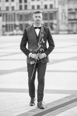 Smokinli zarif bir damat. Dışarıda smokin giyen bir damat. Kırmızı güllü yakışıklı damat..