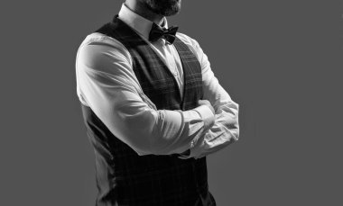 Zarif siyah takım elbiseli şık bir adam. Smokinli bir beyefendi. Resmi etkinlikteki iş adamı. Damadın smokin tarzı var. Centilmen smokini. Smokin, kesilmiş. Papyonlu adam gride izole edilmiş. Terzi kıyafeti..