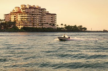 Marinaya yüzen bir tekne. Fisher Adası 'nda lüks bir yat teknesi. Yaz tatili. Fisher Adası konut binası ve lüks yat teknesi. Miami 'de Fisher Adası' na yat gezisi..