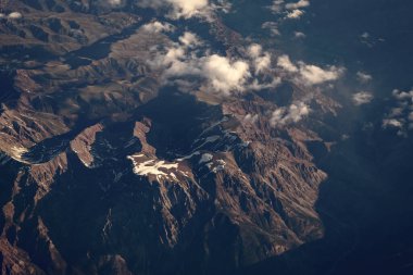 Dağlı, bulutlu bir manzara. Bulut ve dağ zirvesi hava manzarası. Dağ manzarasının havadan görünüşü. Hava bulutlu görünüyor. Uçaktan manzara. Dağların tepesinde, bulutların içinde. Manzara Görünümü.