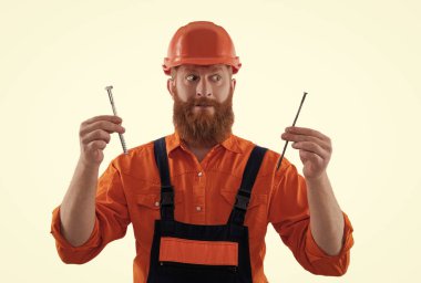 Tamirci. Adam çekiç çivisi tutuyor. Marangozluk tamir ve çekiç. Üniformalı tamircinin çivisi var. Sakallı marangoz çivi tutar. Marangoz, çivi beyazı ile onarıyor. İnşaat ve çerçeve.