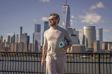 Spor aktivitesi. Yoga koçu. Sporcu adam antrenmana hazır. Sağlıklı bir yaşam tarzı. Spor ve spor. Eğitim için yoga minderi. New York 'ta sporcu. Manhattan 'da spor kıyafetli bir adam..