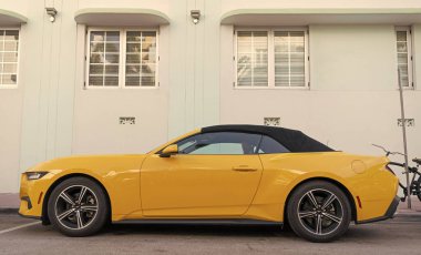 Miami, Florida, ABD - 15 Aralık 2024: Sarı 2024 Ford Mustang EcoBoost üstü açık araba. Ford Mustang 'in lüks arabası. Ford Mustang 'in arabası dışarıda park edilmiş. Ford Mustang sarı renk, köşe görünümü.