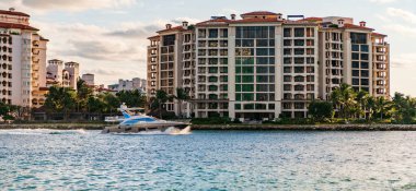Marinaya yüzen bir tekne. Fisher Adası 'nda lüks bir yat teknesi. Yaz tatili. Fisher Adası konut binası ve lüks yat teknesi. Miami Fisher Adası Panorama Manzarası.