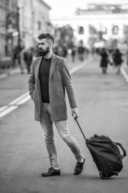 Sakallı şık bir adam şehir caddesinde seyahat çantası ya da bavuluyla iş seyahatine çıkıyor, iş adamı seyahat ediyor..