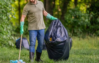 Çevre koruma ve atık kirliliği. Çevre plastik kirliliği. Ormandaki çöpleri çöp torbasına toplayan bir gönüllü. Çevresel koruma. Çevre eylemcisi. Doğa kaydediliyor.