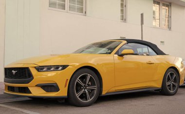 Miami, Florida, ABD - 15 Aralık 2024: Sarı 2024 Ford Mustang EcoBoost üstü açık araba. Ford Mustang 'in lüks arabası. Ford Mustang 'in arabası dışarıda park edilmiş. Ford Mustang sarı renk, köşe görünümü.