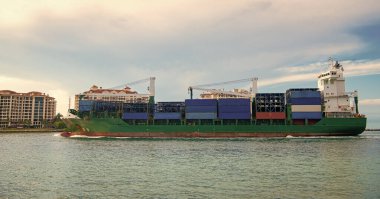 Konteynırlı kargo gemisi. Yük konteynırı kargo gemisine yüklendi. Limandan ayrılan ya da limana giren kargo gemisinin görüntüsü. Kargo işi konsepti. Konteyner gemisi.
