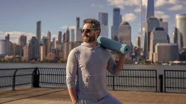 Eğitim için yoga minderi. New York 'ta sporcu. Manhattan 'da spor kıyafetli bir adam. Sağlık ve etkinlik, yoga koçu. Sporcu adam antrenmana hazır. Sağlıklı bir yaşam tarzı. Spor ve spor.