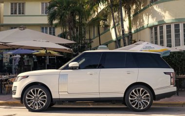 Miami, Florida, ABD - 17 Aralık 2024: Land Rover Range 2018 geçiş aracı. Land Rover 'ın lüks aracı. Beyaz araba Range Rover 'ı dışarıda park etmiş, köşe manzaralı.