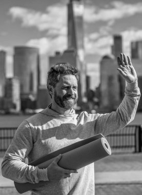 Sporcu adam antrenmana hazır. Sağlıklı bir yaşam tarzı. Spor ve spor. Eğitim için yoga minderi. New York 'ta sporcu. Manhattan 'da spor kıyafetli bir adam. Yogaya hoş geldiniz. Yoga koçu. Merhaba..