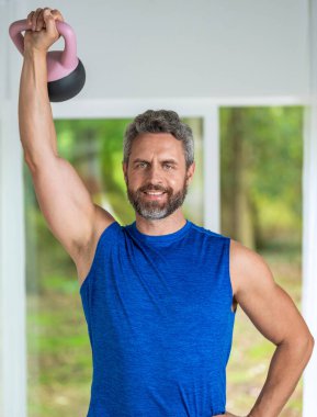 Sporcu, kettlebell 'le antrenman yapıyor. Antrenör spor salonunda ağırlık kaldırmak için kettlebell kaldırır. Dayanıklılık ve fitness eğitimi. Spor salonu egzersizi, motivasyon. Spor belirleme.