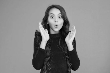 Kız şaşırmış ve şok olmuş hissediyor. Ergen çocukluğu. Şaşırdım kaldım. Kıvırcık saçlı genç kız portresi. Sürprizi ifade eden genç bir kız. Uzun saçlı, şaşırmış bir genç kız..