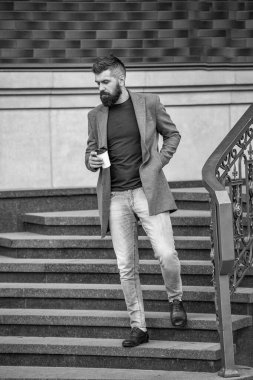 Kahve molası. Günlük stil rutini. Sakallı adam şehir caddesinde kahve içiyor. Sokakta elinde kahve tutan yakışıklı bir adam. İş hayatı, mola. Sabah kahvesi içen adam. Çalışma gününden sonra.