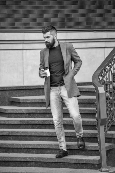 Kahve molası. Günlük stil rutini. Sakallı adam şehir caddesinde kahve içiyor. Sokakta elinde kahve tutan yakışıklı bir adam. İş hayatı, mola. Sabah kahvesi içen adam. Çalışma gününden sonra.