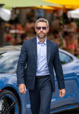 Takım elbiseli hırslı bir işadamı. İş adamı portresi. Başarılı bir iş ve liderlik. Girişimci başarısı. Zengin işadamı arabadan dışarı çıkıyor. Başarılı iş adamı lideri.