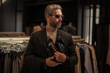 Ayakkabı mağazasındaki tezgahtar adam klasik ayakkabıları tutuyor. Ayakkabı mağazası. İş adamı ayakkabıyı dükkanda seçer. Resmi görünmek için klasik deri ayakkabılar. Resmi ayakkabı. Deri ayakkabılar. Boyut konusunda yardım.