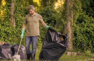 Çevresel koruma. Çevreci adam. Çevresel koruma. Çevreyi koru. Çevre plastik kirliliği. Gönüllü adam ormanda çöp topluyor. Çöp toplama günü.