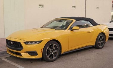 Miami, Florida, ABD - 15 Aralık 2024: Sarı 2024 Ford Mustang EcoBoost üstü açık araba. Ford Mustang 'in lüks arabası. Ford Mustang 'in arabası dışarıda park edilmiş. Ford Mustang sarı renk, köşe görünümü.