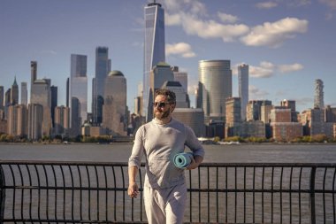 Sporcu adam antrenmana hazır. Sağlıklı bir yaşam tarzı. Spor ve spor. Eğitim için yoga minderi. New York 'ta sporcu. Manhattan 'da spor kıyafetli bir adam. Yoga koçu. Atletik egzersiz.