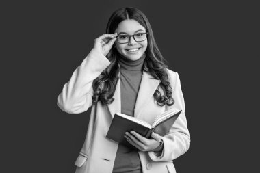 Kız kitap okuyor. Okuma öğrencisi. Gözlüklü liseli kız kitap okuyor. Bilgi ve eğitim. Okula dönelim. Sonbahar montlu ergen kız kırmızıda izole edilmiş. Kitap okuyucu. 1 Eylül.