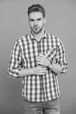 Milenyum erkeğinin gündelik tarzı. Sıradan tişörtlü bir adamın portresi. Tıraşsız adamın zarif portresi. Gri yolda izole edilmiş bir adam. Kareli gömlek giyen milenyum adamı. Minimalist stil.