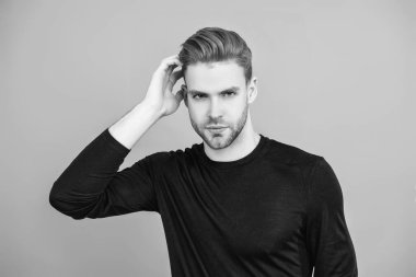 Adamın şık bir saç kesimi var. Moda saç stili olan bir adam. Sıradan erkek tarzı. Beyazlı genç bir adam gri yolda izole edilmiş. Kendine güvenen adam portresi. Erkeklerin cilt bakımı. Erkek derisi. Kuaför..