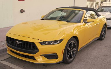 Miami, Florida, ABD - 15 Aralık 2024: Sarı 2024 Ford Mustang EcoBoost üstü açık araba. Ford Mustang 'in lüks arabası. Ford Mustang 'in arabası dışarıda park edilmiş. Ford Mustang sarı renk, köşe görünümü.
