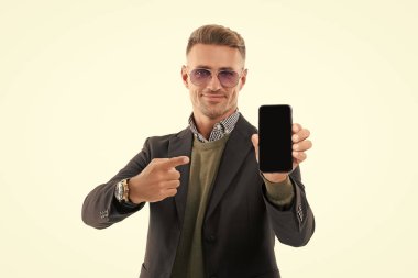 İş adamı, telefonun beyazda izole olduğunu gösteriyor. Adam yeni iş telefonu uygulamasını gösteriyor. Ürünü sunuyorum. İşaret parmağı. İş uygulamasının reklamı. Olgun iş adamı telefon ekranı sunar.