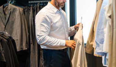 Modaya uygun bir ceket. İspanyol işadamı terziliği seçiyor. Bespoke terziliği. Takım elbiseli bir erkek model. Perakende satış asistanı şık bir adamın takım elbise bulmasına yardımcı olur. Takım elbiseli şık bir adam, kırpık manzaralı..