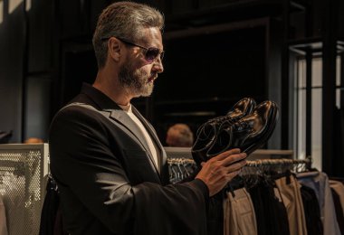 Deri ayakkabılar. Ayakkabı mağazasındaki tezgahtar adam klasik ayakkabıları tutuyor. Ayakkabı mağazası. İş adamı dükkanda şık ayakkabılar seçer. Resmi görünmek için klasik deri ayakkabılar. Resmi ayakkabı. Teklif edilen ayakkabılar.