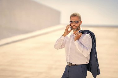 İş adamının telefon görüşmesi var. Reklamlar. Telefon kullanan bir iş adamı. İş görüşmesi. Meşgul iş adamı telefonda konuşuyor. Ofis çalışanı dışarıda telefonla konuşuyor. Akıllı telefondan iş adamı konuşması.