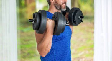 Kas gücü. Güçlü trisepsler. Dambılla egzersiz yapan bir adam. Erkek atlet dambılı kaldırıyor. Güçlü adam spor egzersizi yapar. Jimnastik. Dambılı bir sporcu. Sağlıklı bir yaşam tarzı. Kırpılmış görünüm.