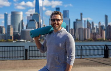 Spor ve spor. Eğitim için yoga minderi. New York 'ta sporcu. Manhattan 'da spor kıyafetli bir adam. Vücuduna uygun. Yoga koçu. Sporcu adam antrenmana hazır. Sağlıklı bir yaşam tarzı. Beden paspası.