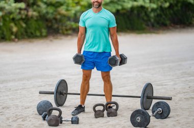 Güçlü adam spor egzersizi yapar. Jimnastik. Dambılı bir sporcu. Sağlıklı bir yaşam tarzı. Kas gücü. Güçlü trisepsler. Dambılla egzersiz yapan bir adam. Dambıl kaldıran erkek sporcu, kırpık manzara..