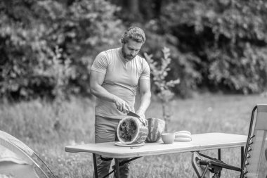 İspanyol olgun bir adam yaz kampı pikniğinde yemek için karpuz kesti. Lezzetli ve sağlıklı..