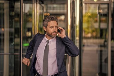 Patrona telefon var. İletişim ve müzakere. İş adamı dışarıda telefonla konuşuyor. İş adamının telefonu var. Ofiste iş görüşmesi. İş görüşmesi çağrısı. Şirket işi..