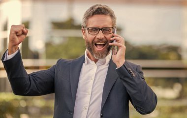 Telefonu olan heyecanlı bir İspanyol iş adamı. İş iletişimi. Müzakere çevrimiçi. İş adamı dışarıda telefonla konuşuyor. Telefon kullanan bir iş adamı. Takım elbiseli adam telefonu..