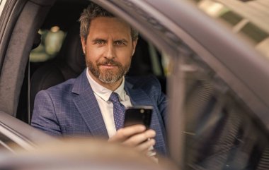 Takım elbiseli bir adam arabada telefon kullanıyor. Telefonu olan İspanyol bir işadamı. Başarılı bir bayilik. İş adamının telefonu var. Araba sigortası. Başarılı bir araba satıcısı. Satış. Lüks araba yolculuğu..