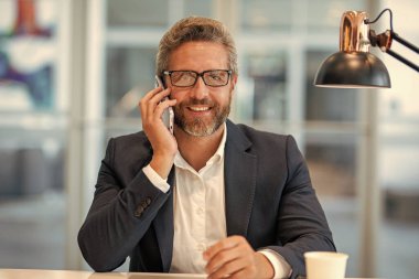 Telefon kullanan bir iş adamı. Takım elbiseli bir adam telefonda konuşuyor. Telefonu olan olgun bir İspanyol iş adamı. İş iletişimi. Müzakere çevrimiçi. İş adamı telefonda konuşuyor..