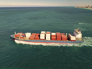 Yük konteynırı kargo gemisine yüklendi. Limandan ayrılan hava görüntülü kargo gemisi. Kargo işi. Konteyner gemisi. Nakliye lojistiği. Ticari nakliye. Kargo gemisi denizde, hava manzaralı..